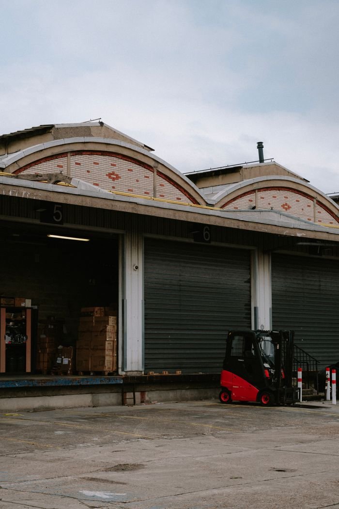 The Art of Drawing Readers In: Your attractive post title goes here A red forklift parked at a warehouse loading dock with closed garage doors.